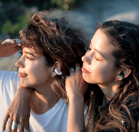 Person relaxing and listening to audio with ear clip bone conduction headphones.